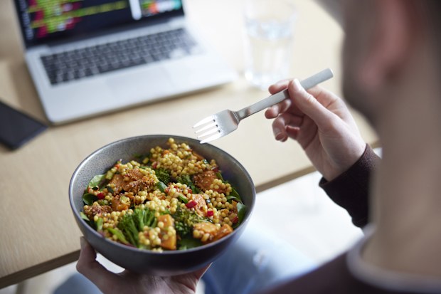 Close Of Man Eating Healthy Vegan Lunch At Office Whilst Using Laptop office lunch