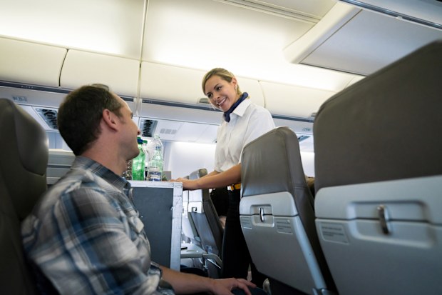 Portrait of a friendly flight attendant serving food and drinks in an airplane and looking happy - travel concepts