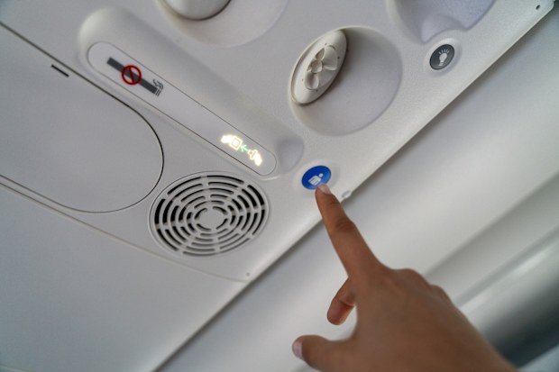 Woman hand pressing the button in the passenger air plane to call flight attendant, cabin crew for a service.