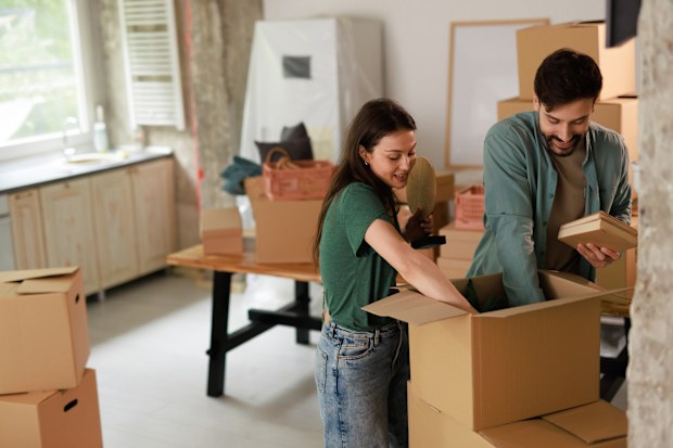 Happy young couple unpacking belongings from cardboard boxes in their new apartment, embracing the excitement of starting a life together and creating lasting memories
