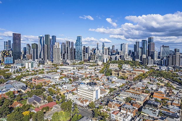 Not the usual cityscape view of Melbourne: aerial view of Melbourne's growing wide cluster of CBD skyscrapers taken from North Melbourne showing the contrast of old and new architecture in the foreground. Tree-lined streets low-rise buildings and parklands in established older suburb.