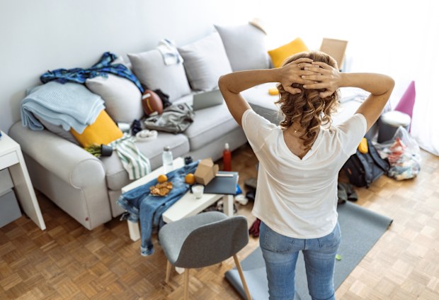 Woman looking at her messy loungeroom, cleaning
