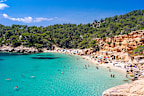 Wide-angle view of Cala Saladeta, a few steps from Cala Salada, on the western coast of Ibiza, renowned for its extremely transparent waters, pearly sands and a scenic group of fishermens huts (locally known as casitas varadero). Bathers engaged in different activities, the bright light of a summer noon, picturesque clouds, colourful cliffs, lush vegetation. Developed from RAW.
