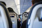 Interior of an airplane cabin with passengers sitting in rows of seats. Air travel and transportation concept.