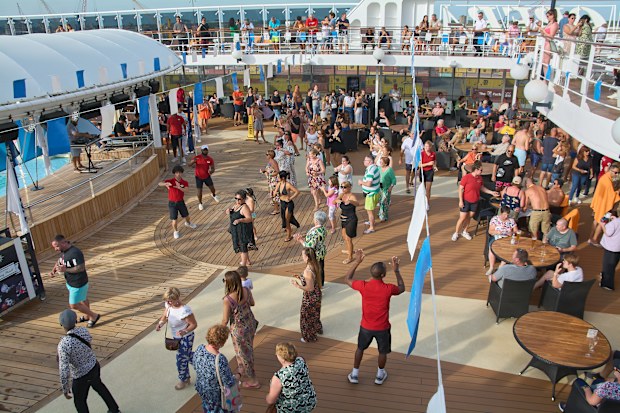 Venice. Italy - September 23, 2025: A group of adults is enjoying a dance party on the top deck of a ship. a perfect setting for vacation fun.