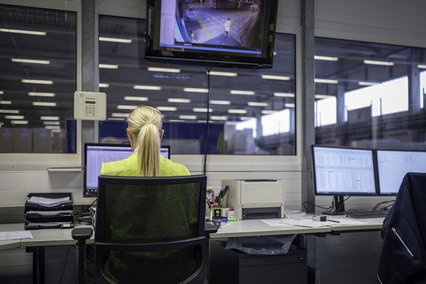 Female caucasian shipping operator managing orders on computer while working in warehouse office, medium shot back view