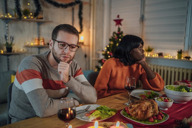 Young unhappy multi ethnic couple ignoring each other after an argument during Christmas dinner