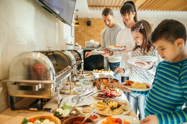 Family taking food in self service restaurant in hotel. A lot of domestic colorful food is served. Family with two children.