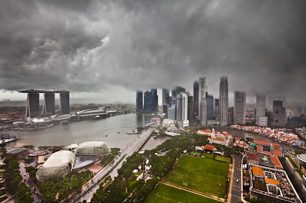 Thunderstorm with heavy dark clouds and rain over the skyline of Singapore. Falling rain and some grain are visible.
