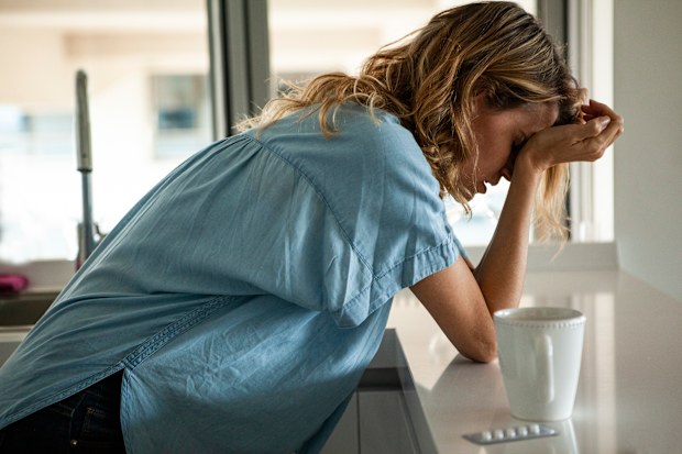 Portrait of stressed woman with head in hands standing indoors during daytime
