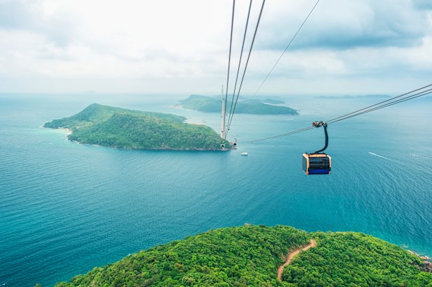 Cable car cabin gliding over turquoise sea and green tropical island. Longest Hon Thom cable car ride in the world on Phu Quoc island, Vietnam. Modern tourism technology and infrastructure.