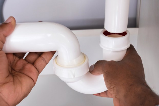 Close-up Of Plumber Fitting Sink Pipe In Kitchen At Home