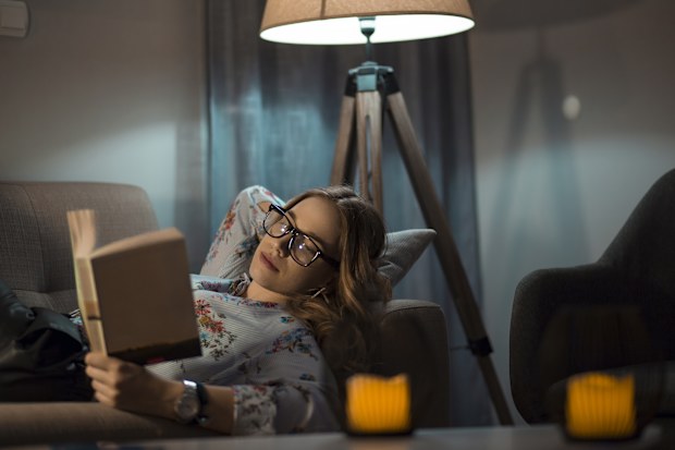 Beautiful female reading favourite book at night