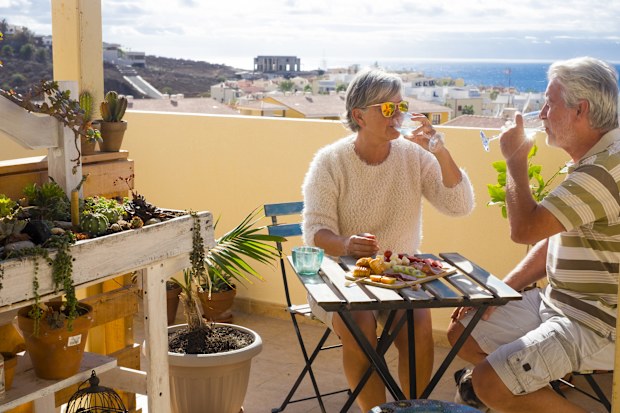 nice couple of retired adult stay together on the rooftop terrace eating and drinking some food and drin