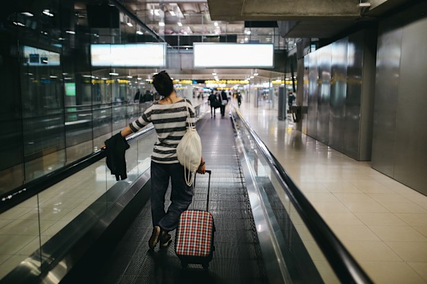 Image of a young woman with a suitcase traveling solo. Taken at the Bangkok airport.