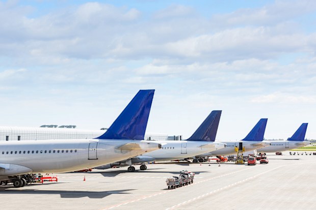 Tails of some airplanes at airport during boarding operations. They are four planes on a sunny day, with a blue sky