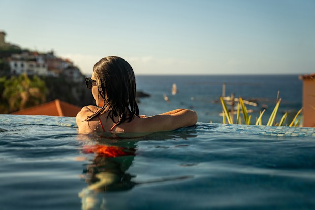Woman relaxing in the swimming pool. Tourist resort with the view of marine. Madeira island