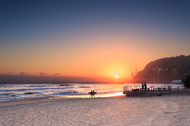 coulpe surfers walks along the beach in Burleigh Heads (Gold Coast, QLD, Australia)