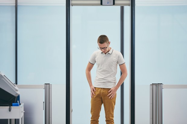 Airport security check. Young man (traveler) in gate of the metal detector.