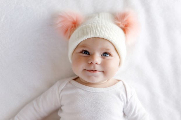 Cute adorable baby girl with warm white and pink hat with cute bobbles
