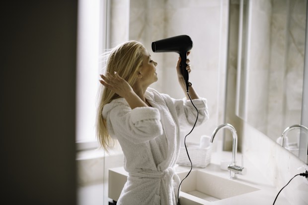 Woman using hairdryer in hotel room 