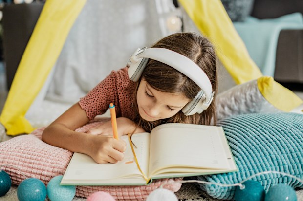 Little cute girl is at home on the floor, she is writing her homework