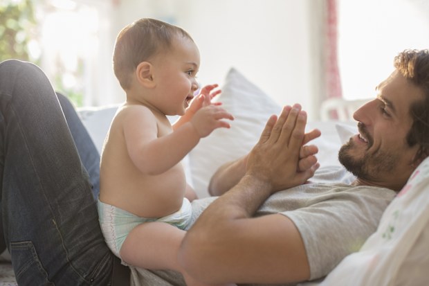 Father playing with son on bed. 