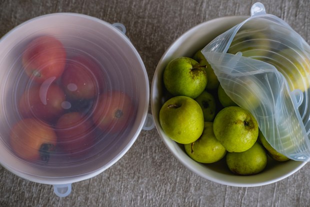 Apples and tomatoes packed with environmentally safe round silicone stretch lids ready for storage. Reusable eco-friendly kitchen products. Zero waste and sustainable plastic free lifestyle