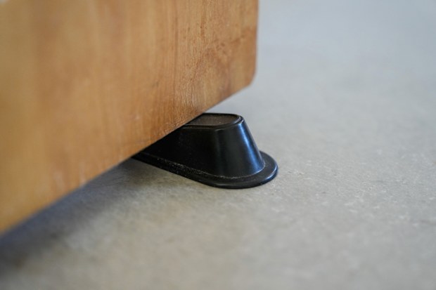 Close up detail of a secure brown rubber doorstop keeping wood door open