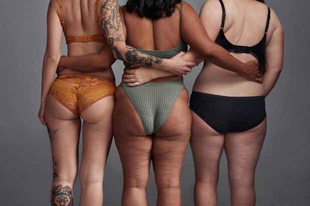 Shot of three young women posing in their underwear against a grey background