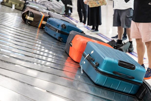 Baggage luggage at airport arrival carousel with passengers patiently awiating to claim theirs