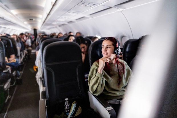 Young woman listening to music while traveling by plane, enjoying the relaxing moment