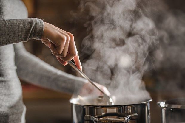 Unrecognizable woman stirring soup in a saucepan while making lunch. Cooking.