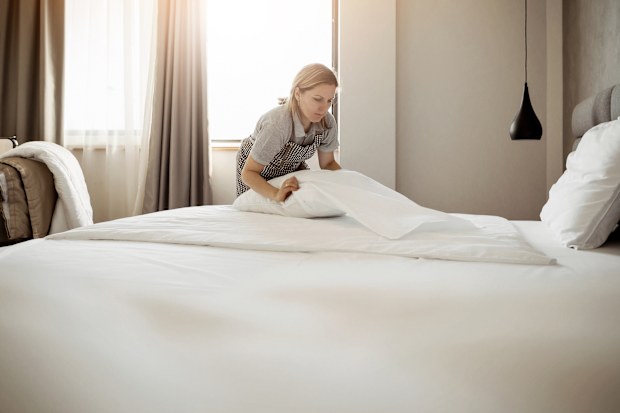 Maid working at a hotel making the bed