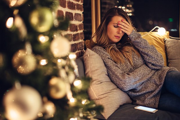 Depressed mid adult woman near christmas tree in her home.