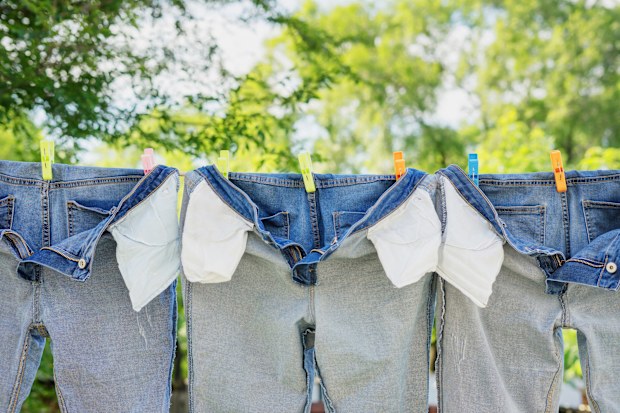The washed jeans hang on a clothesline. Pockets turned inside out. Drying clothes on the street