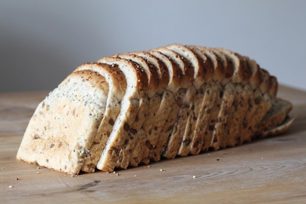 Loaf of seeded bread all sliced on the dining room table. Close details of the different seeds in the loaf. Healthy eating.