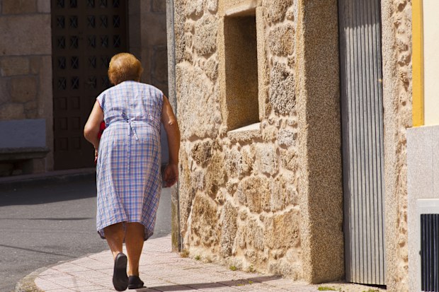 Senior woman walking slowly on sidewalk  . Disabled, aging process. A Coruña province, Galicia,Spain.