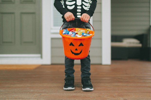 Child in costume holding a Halloween bucket full of sweets