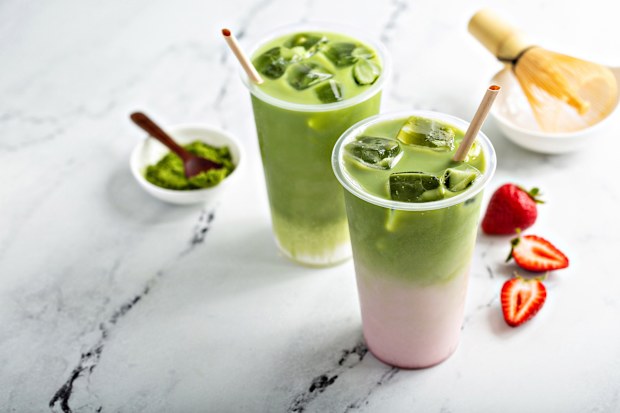 Cold matcha latte in a tall glass with strawberry milk on marble background