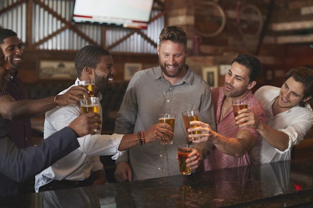 Group Of Male Friends On Night Out For Bachelor Party In Bar Making Toast Together