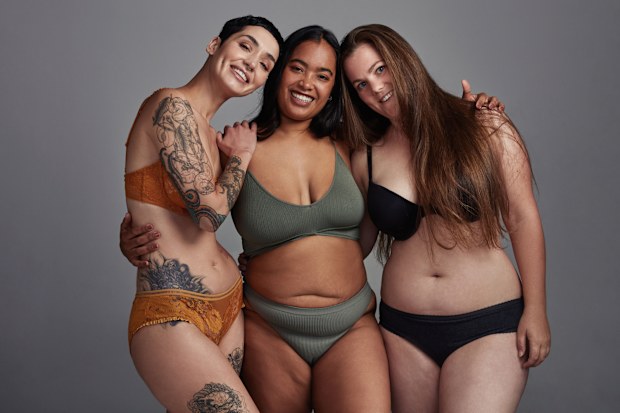 Shot of three young women posing in their underwear against a grey background