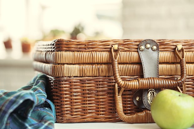 Close up of a wooden basket with dishware on white table
