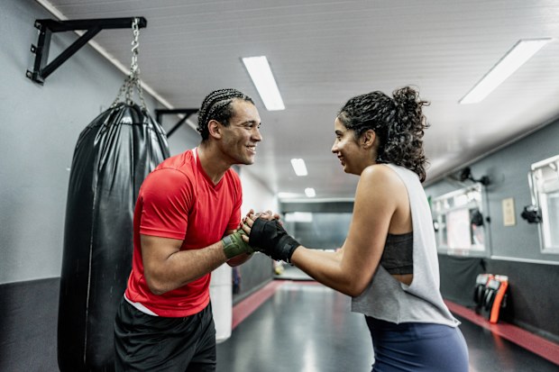 Boxe instructor and mid adult woman greeting at gym