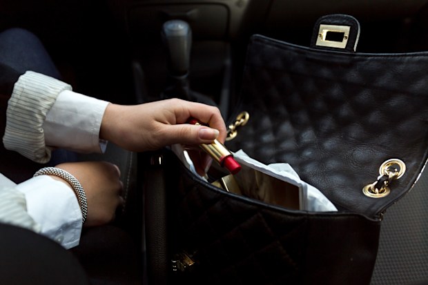 Closeup photo of businesswoman taking red lipstick out of handbag