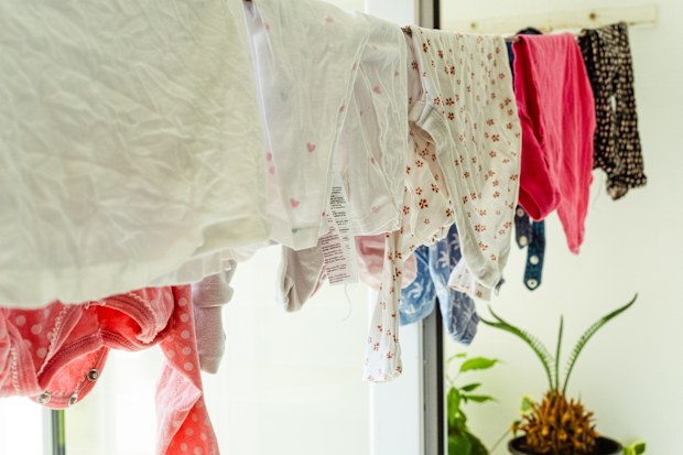 Baby clothes hanging on the clothesline. Toddlers clothes drying on the balcony. Rope with clean kids underwear. Home interior