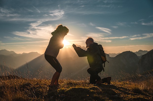 The mountainous backdrop sets the stage for a romantic surprise as a mature couple experiences an engagement proposal, brimming with joy and affection.