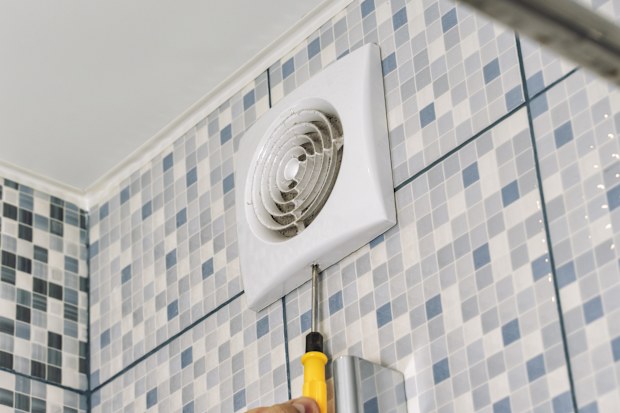 the master removes the ventilation grill in the bathroom with a screwdriver
