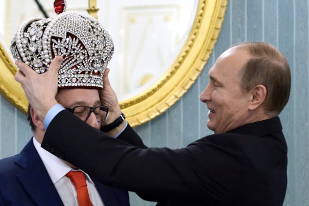 Russian President Vladimir Putin puts a replica of the Imperial Crown on comedian Gennady Khazanov during a Kremlin meeting marking Khazanov's 70th birthday, in Moscow, Russia, Tuesday, Dec. 1, 2015.
