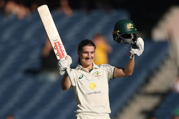 Annabel Sutherland of Australia raises her bat after her century on the MCG.